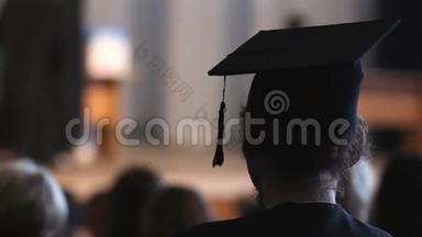 卷发男子穿着灰泥板和学术服装看舞台，<strong>毕业</strong>